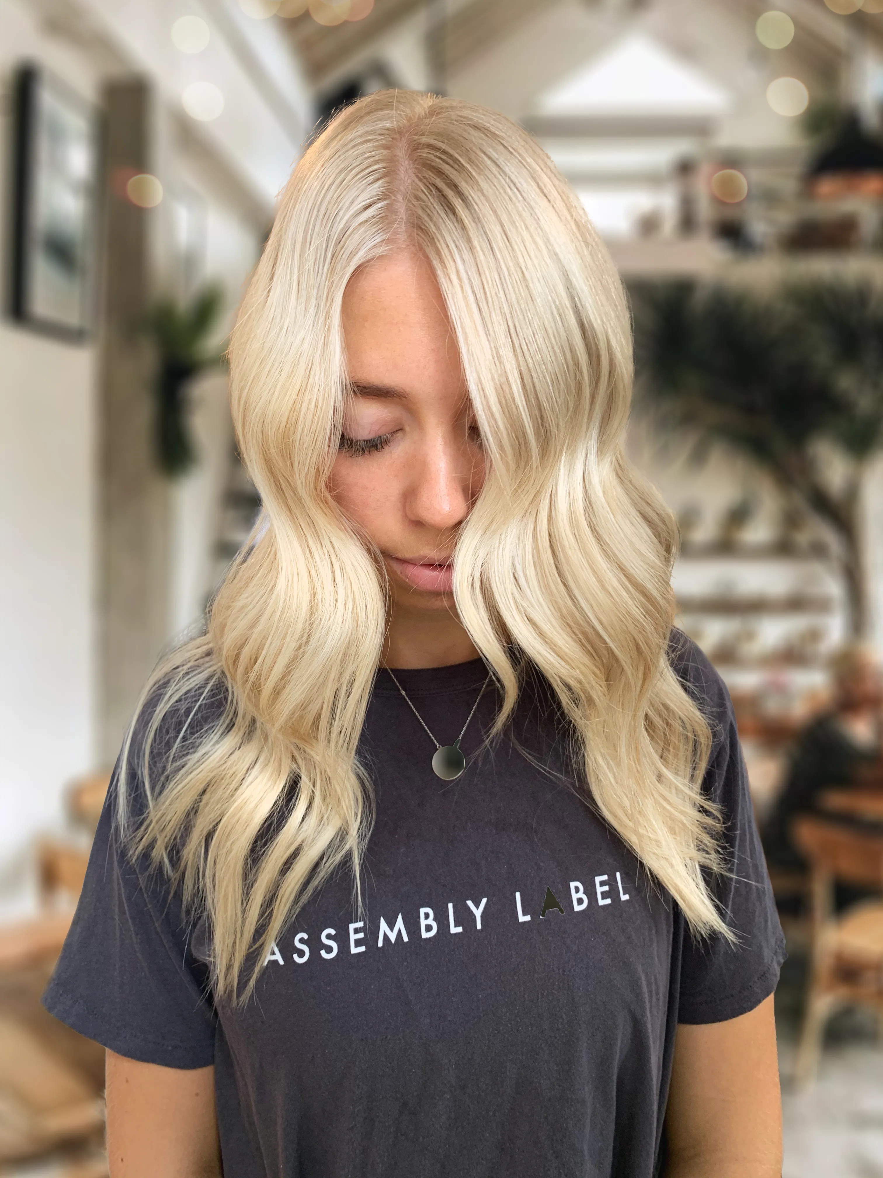 Stylist flat-ironing a client's hair with foliage and orchids